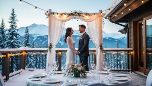 A wedding couple stands under a white arch on a snowy Whistler lodge terrace with an illuminated reception table and mountain peaks in the background.